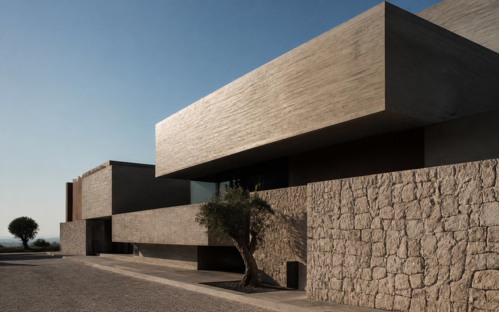 Habitação contemporânea em betão e pedra, com luz rasante ao fim do dia